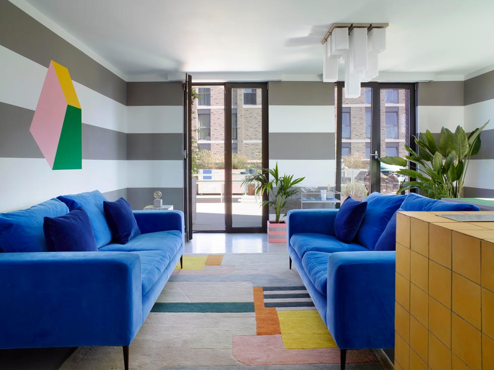 modern living room with grey stripe and pastel abstract wall mural and bright blue sofas