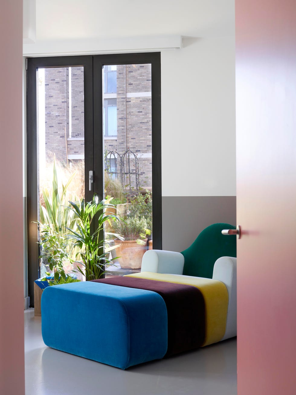 multicolour daybed in sitting area with double doors looking to foliage outside