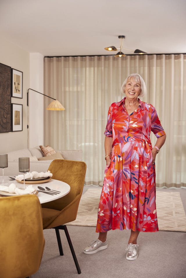 older woman in bright dress indoors looking happy