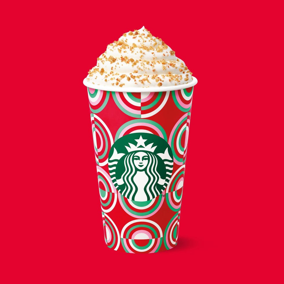 festive starbucks cup with whipped cream and toppings against a red background
