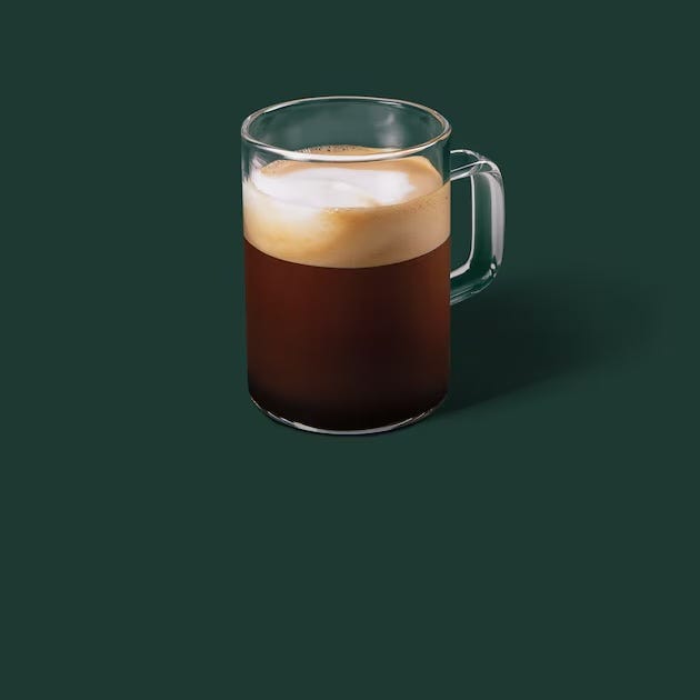 glass mug filled with dark coffee topped with light foam