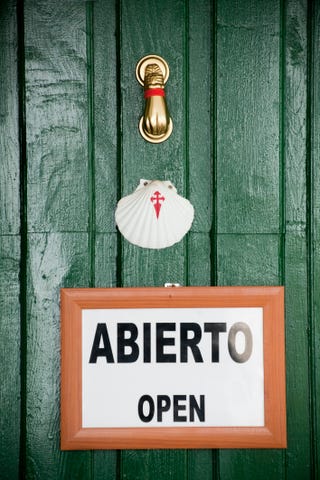 Scallop symbol, open sign and brass knocker on green door.