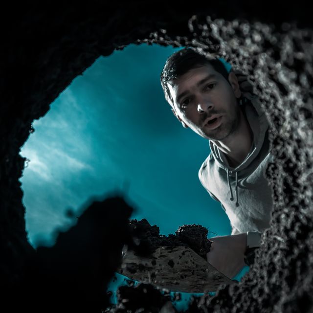 scared guy digging a deep earthen hole with a shovel during a moonlit night