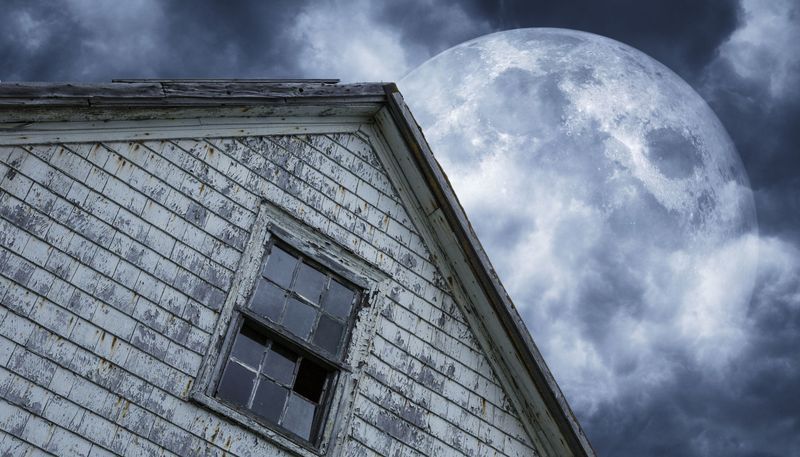 shabby house with moon and clouds above