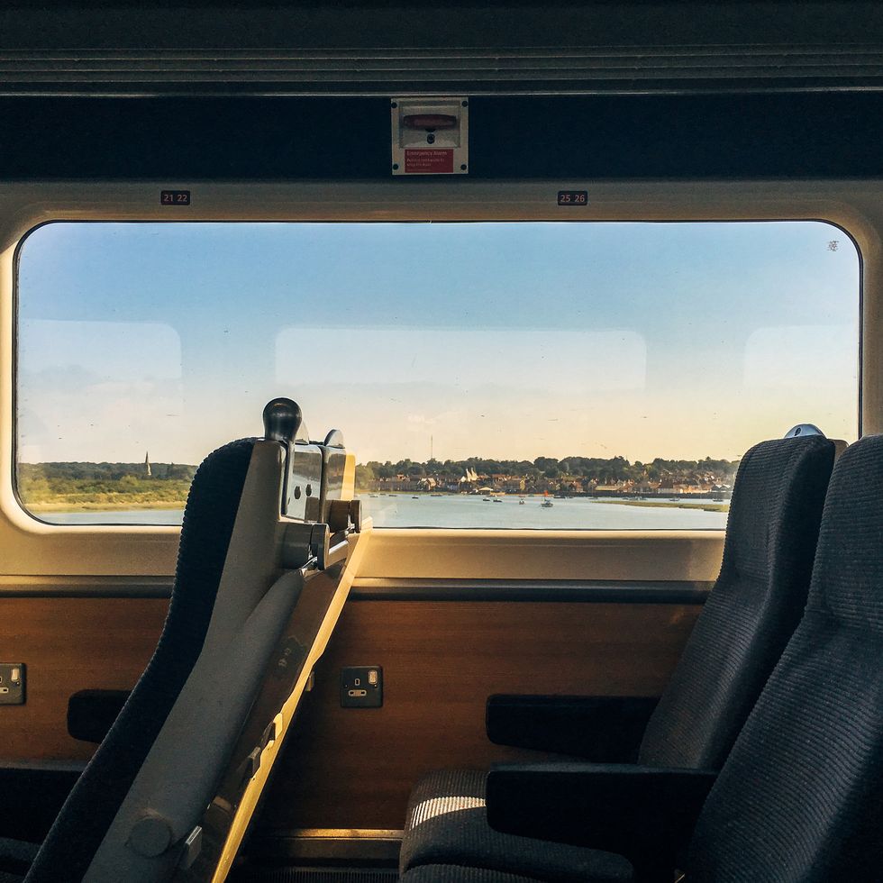 side view of empty passenger seats in a modern train carriage interior with scenic coastal view out of the window at dusk