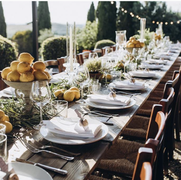 lange tafel met servies, citroenen, wijnglazen en houten stoeltjes bij landgoed rhederoord