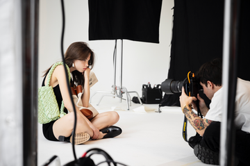 a woman taking a picture of a man sitting on a chair