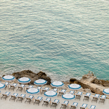 a pool with chairs and umbrellas by a beach