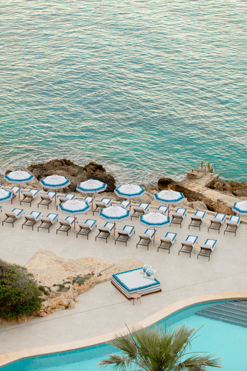 a pool with chairs and umbrellas by a beach