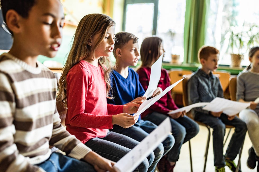 school kids practicing with sheet music on a class at school