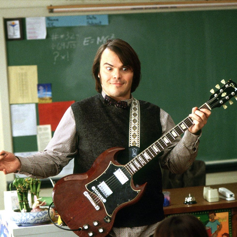 music teacher engaging students while holding a guitar in a classroom