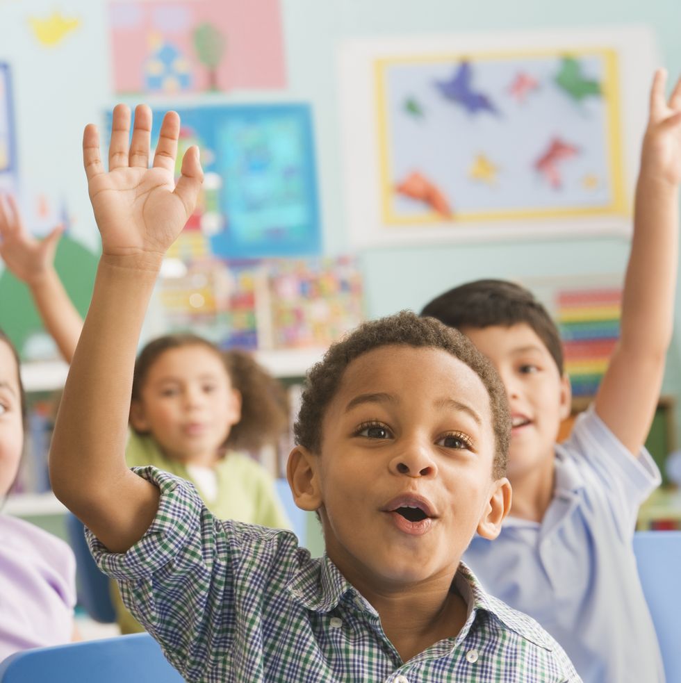 schoolchildren (2 7) in the classroom, hand raised