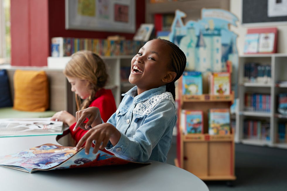 schoolgirls laughing  reading books in school library