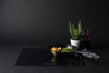 a black frying pan sits on a sleek induction cooktop