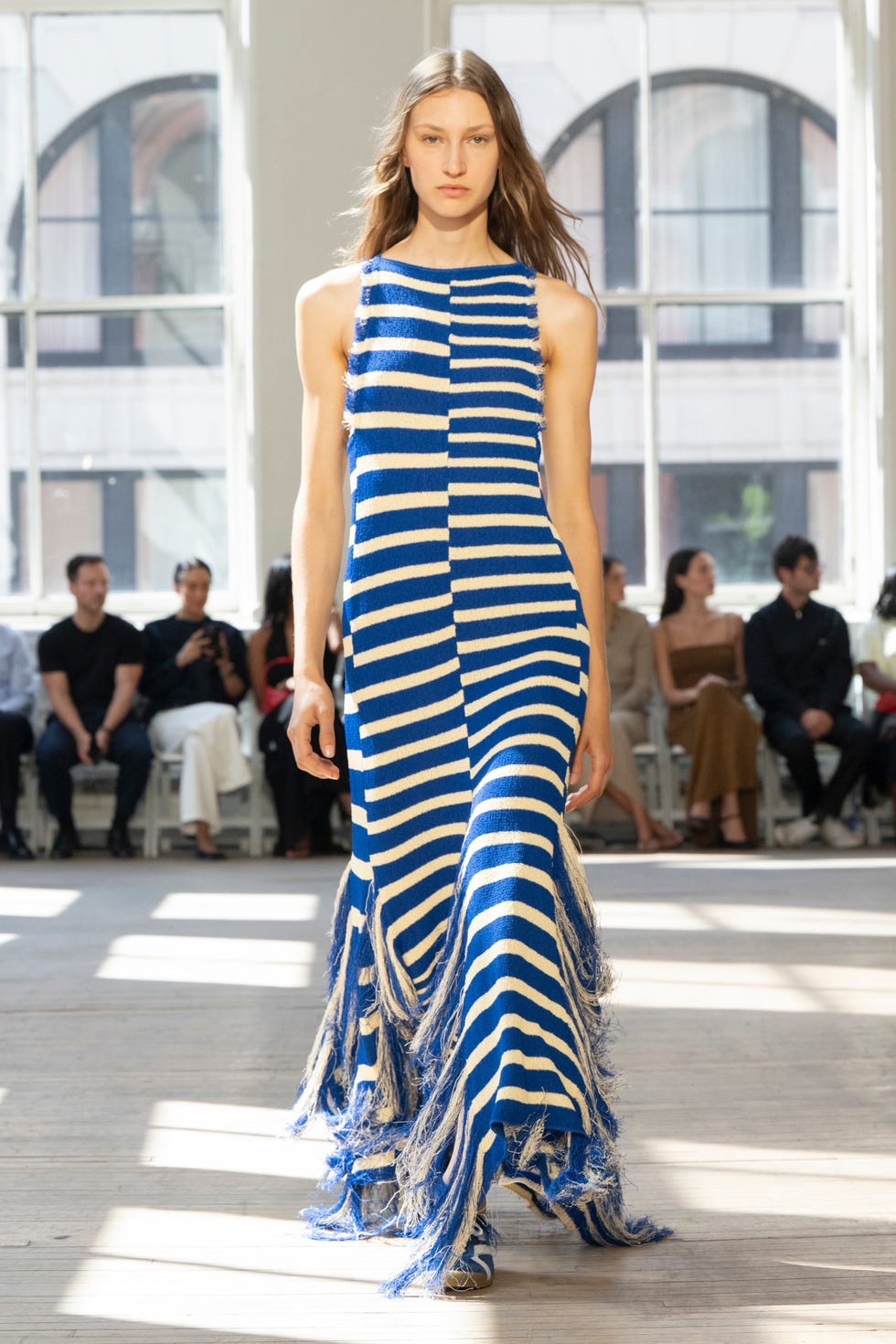 runway model displaying a blue and beige striped dress with fringe