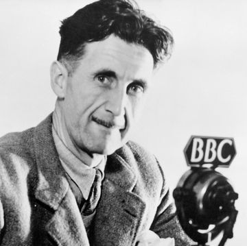 a man smiles at the camera as he wears a suit coat, collared shirt, and tie