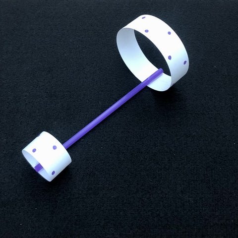 A hoop-and-straw airplane, created as part of a science experiment for kids, sits on a black background a hoop and straw airplane, created as part of a science experiment for kids, sits on a black background