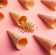 Waffle cones and sprinkles on pink surface empty ice cream waffle cones and colorful sprinkles on pink background, side view
