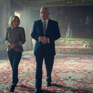 a man and a woman standing in a room with a painting on the wall