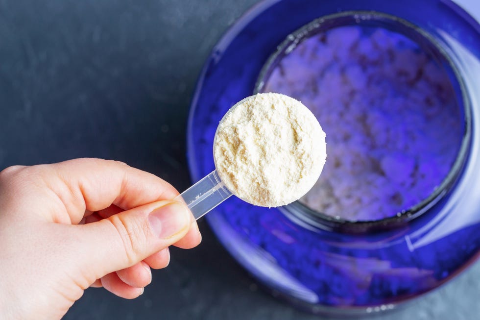 scoop with protein in female hand top view, gray background