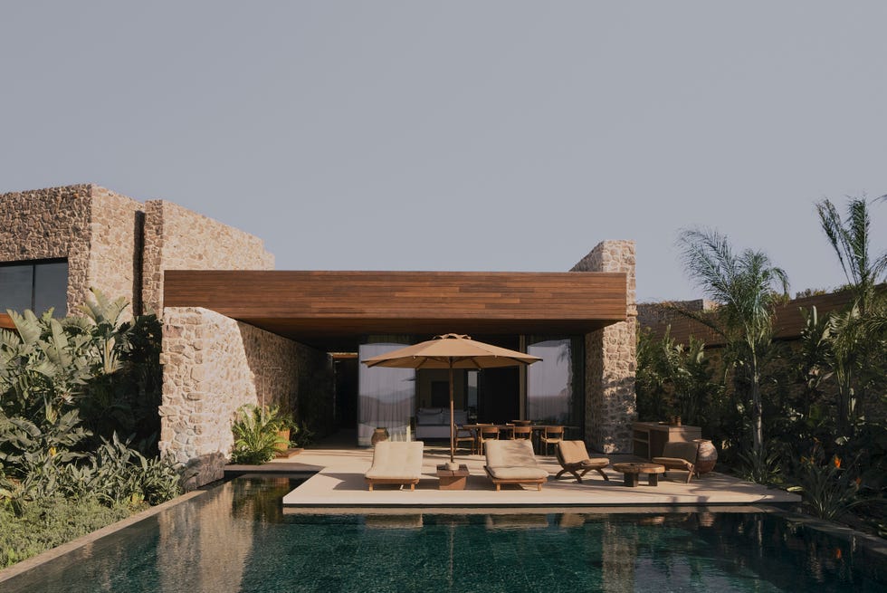 a pool with a lounge chair and umbrella by a building