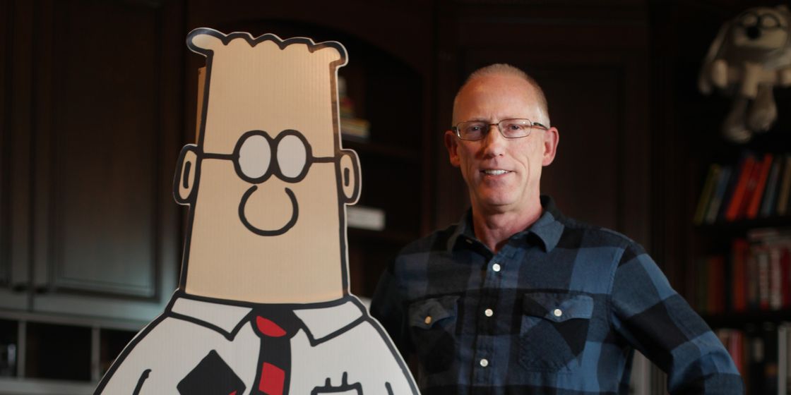 cartoonist scott adams standing with cutout of dilbert comic strip character