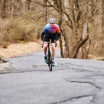 a person riding a bicycle on a road with trees on the side