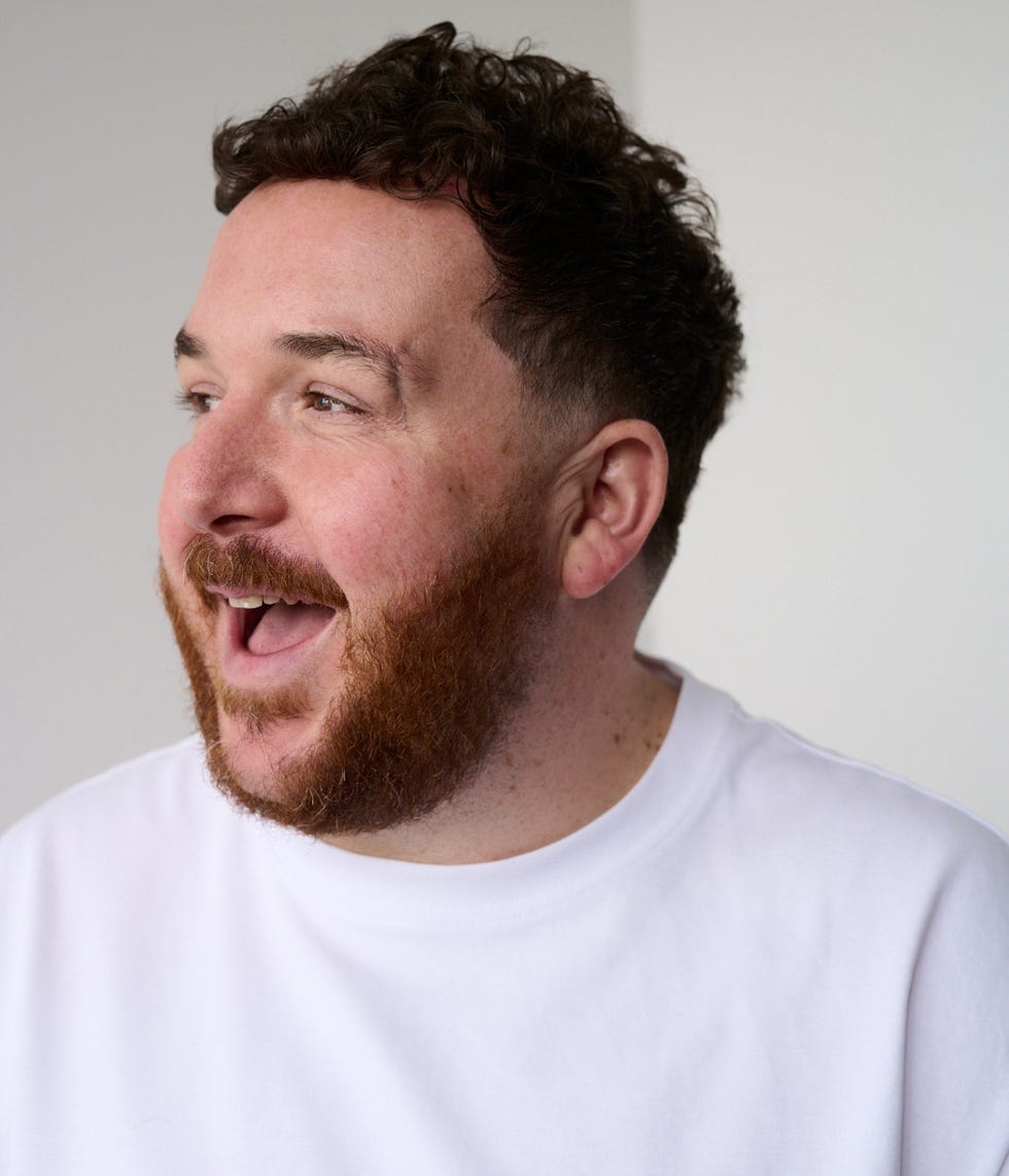 a person with curly hair wearing a white shirt facing slightly to the side