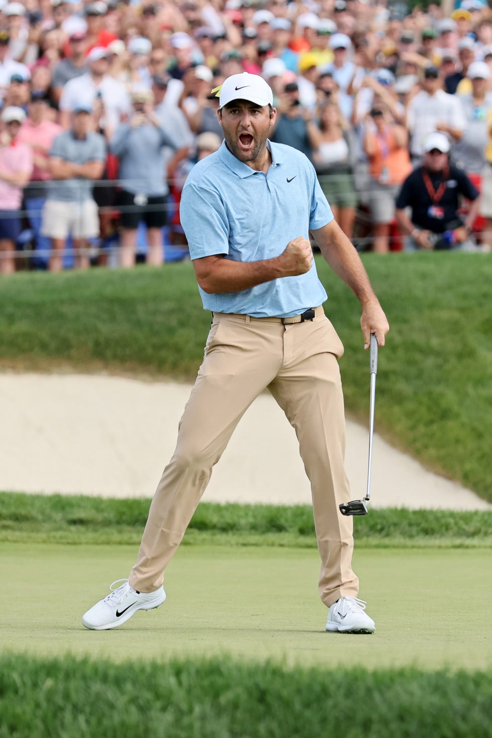 scottie scheffler doing a fist pump and celebrating while standing on a golf green