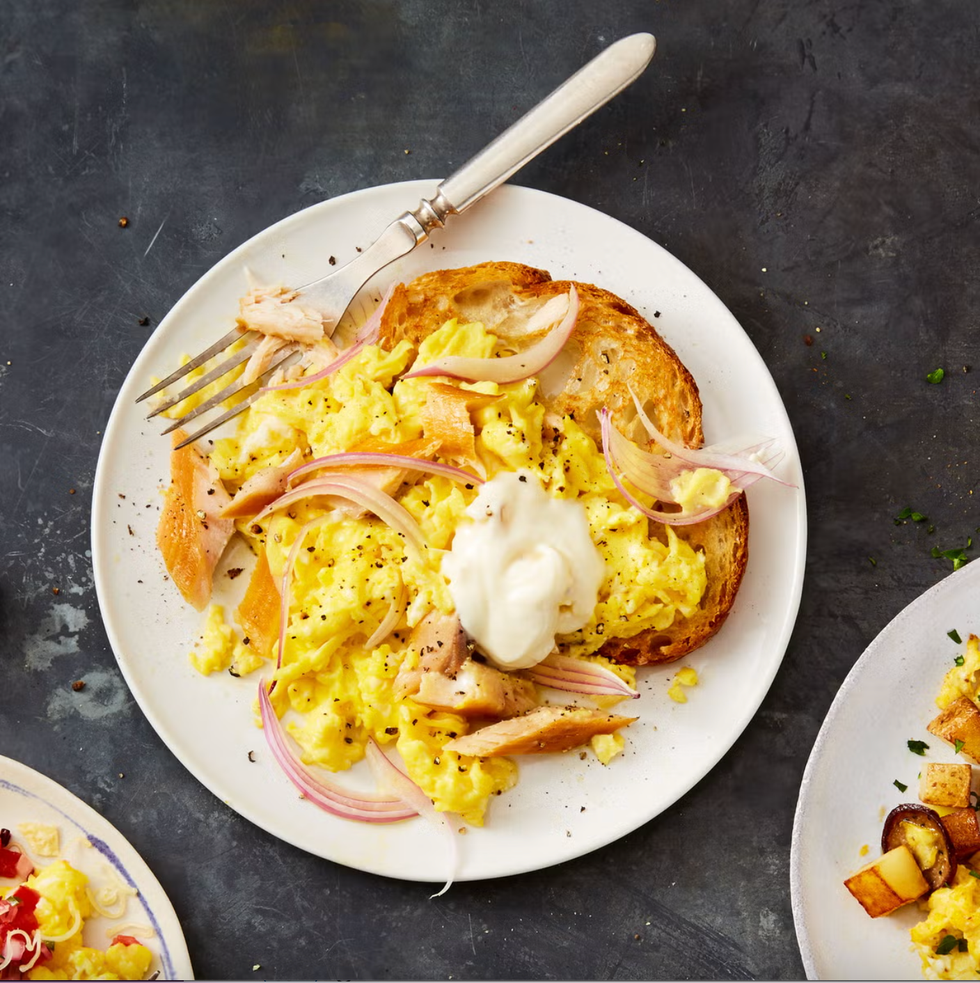 scrambled eggs with smoked trout and creme fraiche on white plate with a fork