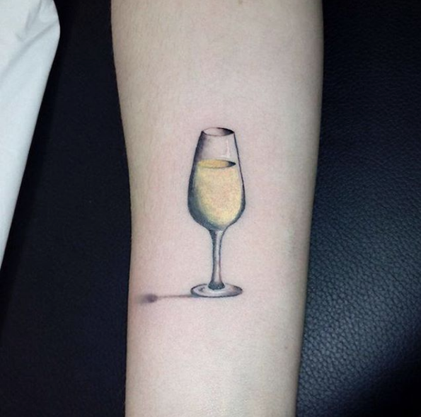 Minimalist wine glass and wave tattoo on the wrist
