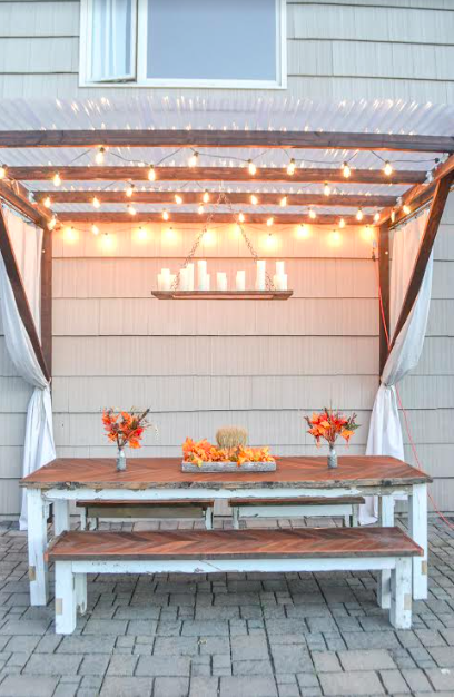wooden bench seating  with table under a pergola and glowing lights