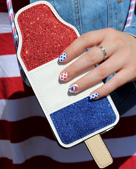 4th of july nail art, hand with painted nails holding a rocketpop shaped bag, good housekeeping's favorite 4th of july activities
