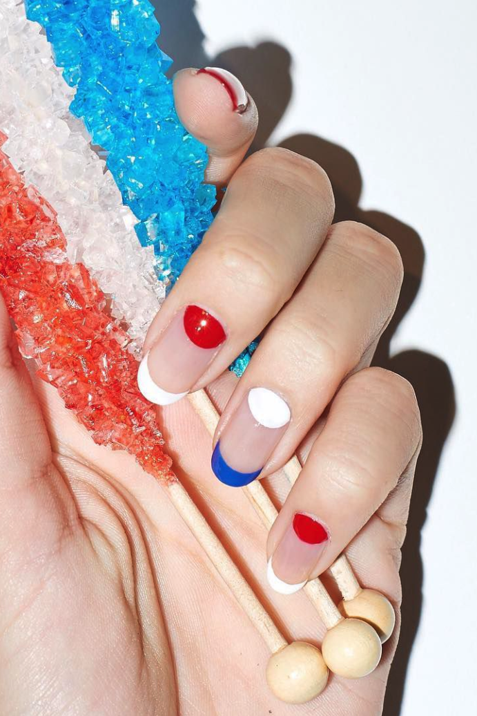 a hand holding candy with a manicure, featuring negative space and red, white and blue colors