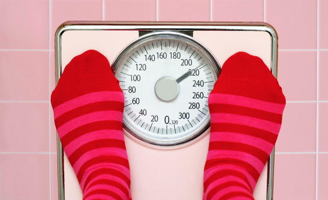 Scales and measuring tape on pink background. Weight loss concept