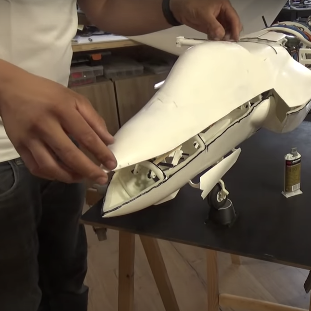 two hands carefully fitting a top piece onto a fighter jet model