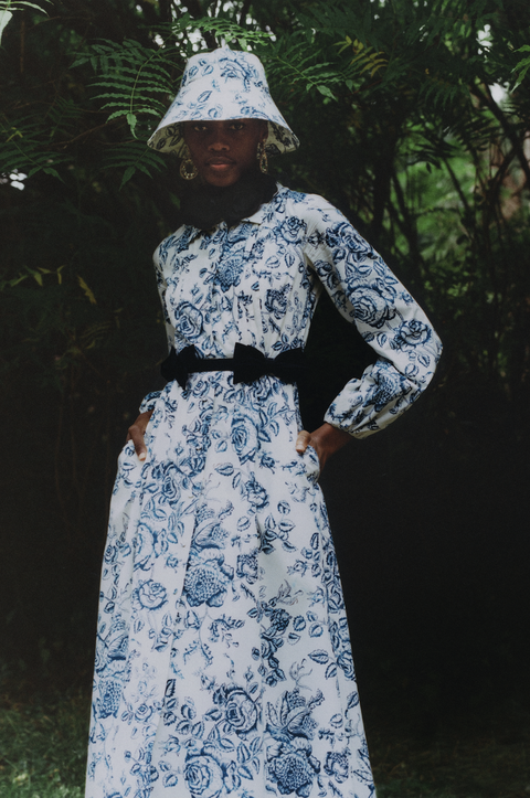 model in blue and white floral dress and hat