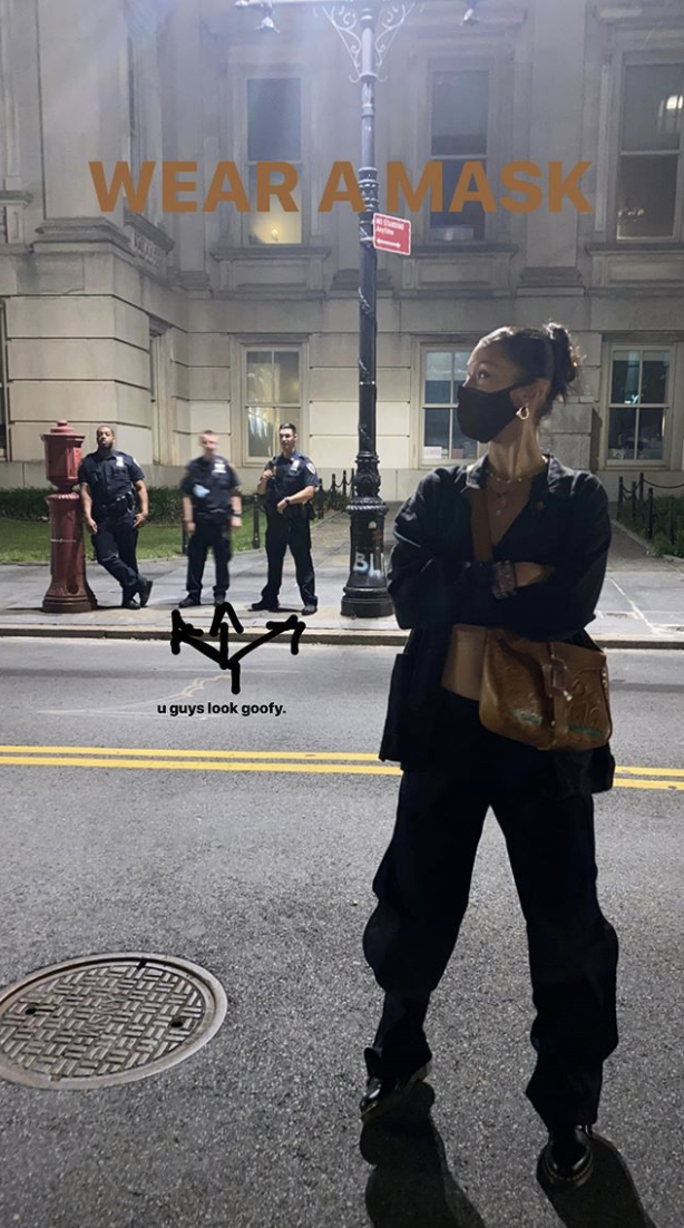 bella hadid stands in front of city hall where group of cops without face masks are gathered