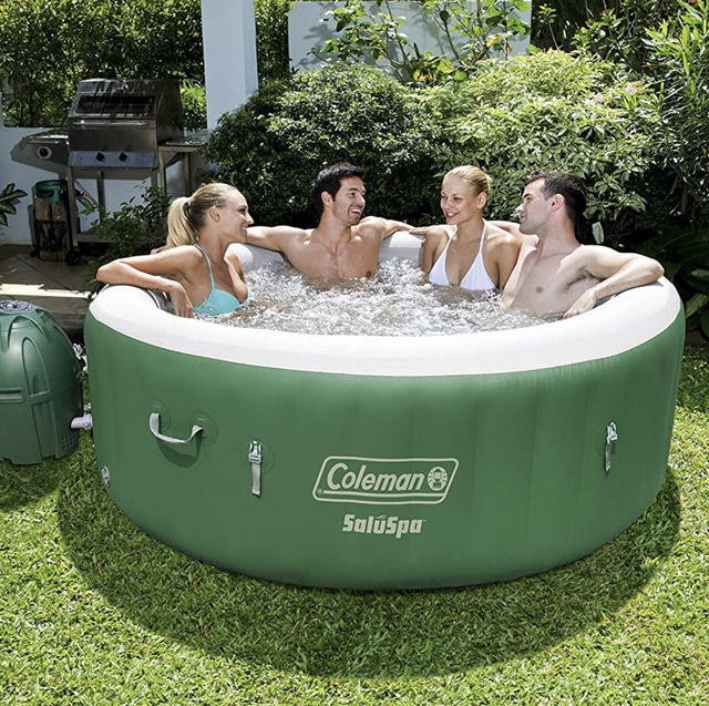 four people in the green and white inflatable hot tub on grass