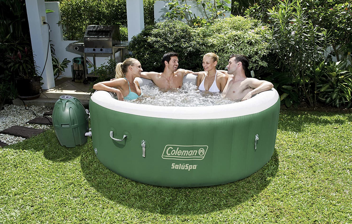 four people in the green and white inflatable hot tub on grass