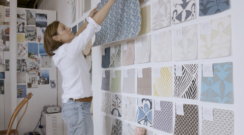 serena dugan hangs a textile pattern on a wall full of rows of other patterns