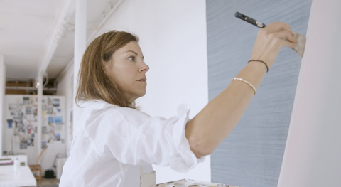 closeup of serena dugan with a paintbrush in hand, painting on a canvas