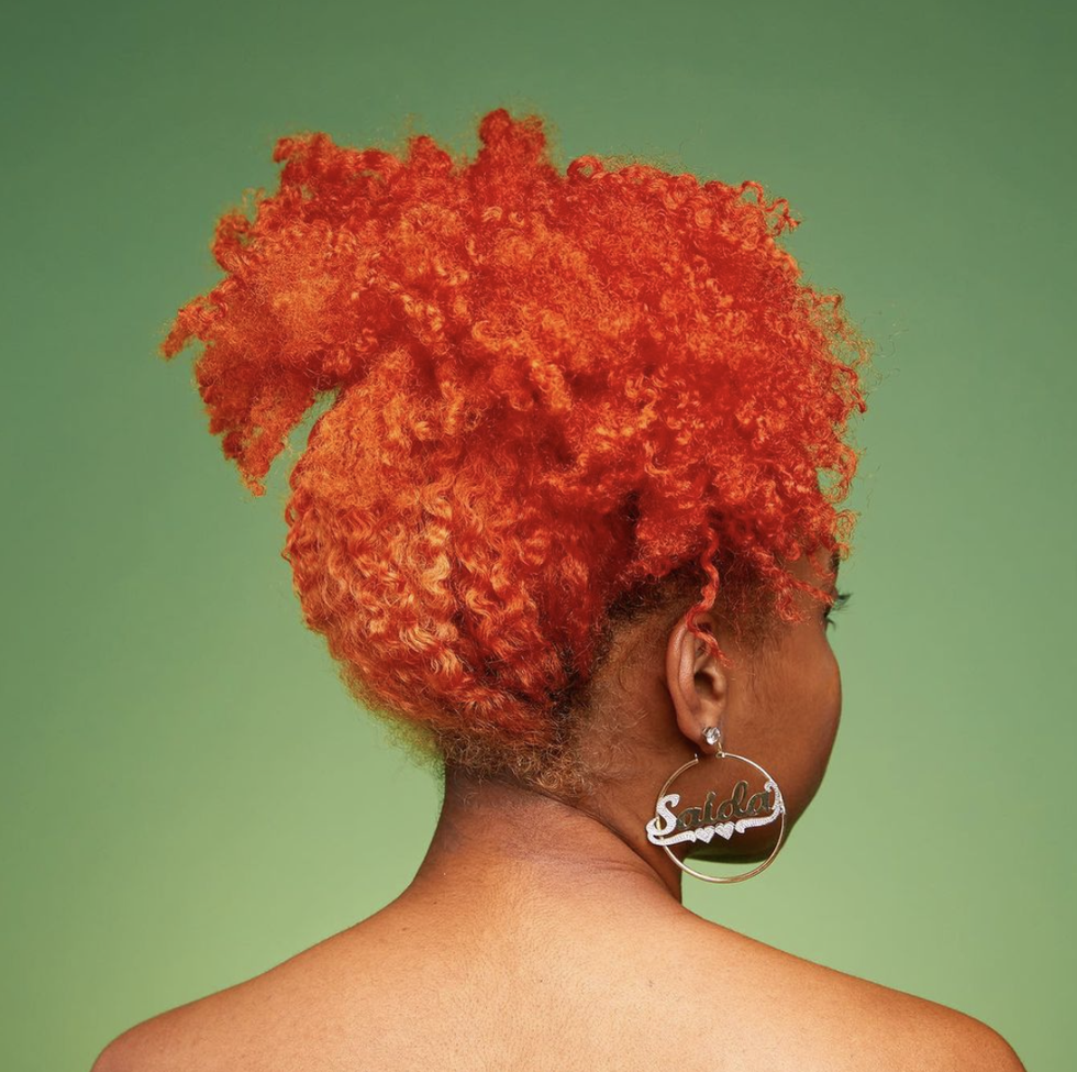 the back of a woman's head, her orange hair pulled back in a ponytail