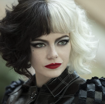 emma stone, a white actress, wears a black and white wig and red lipstick in a still from cruella