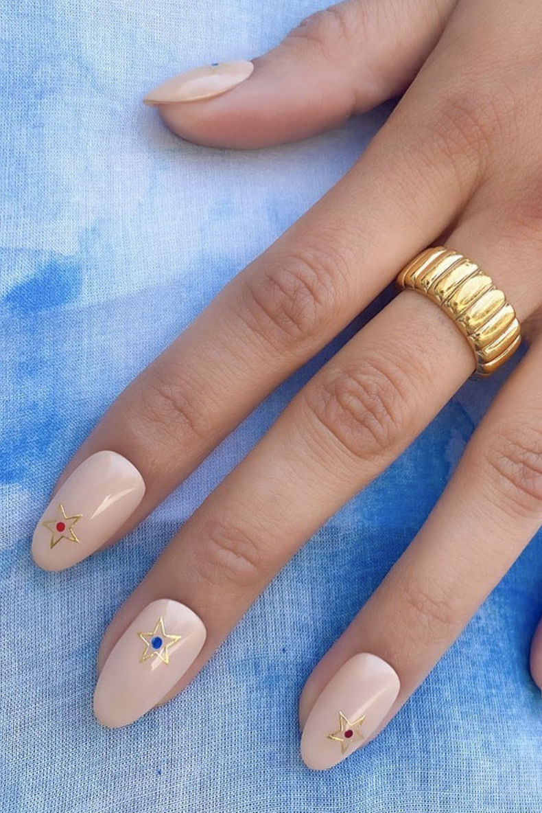 a nude manicure with gold stars on a blue background