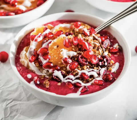 pink smoothie bowl with fruit in a white bowl