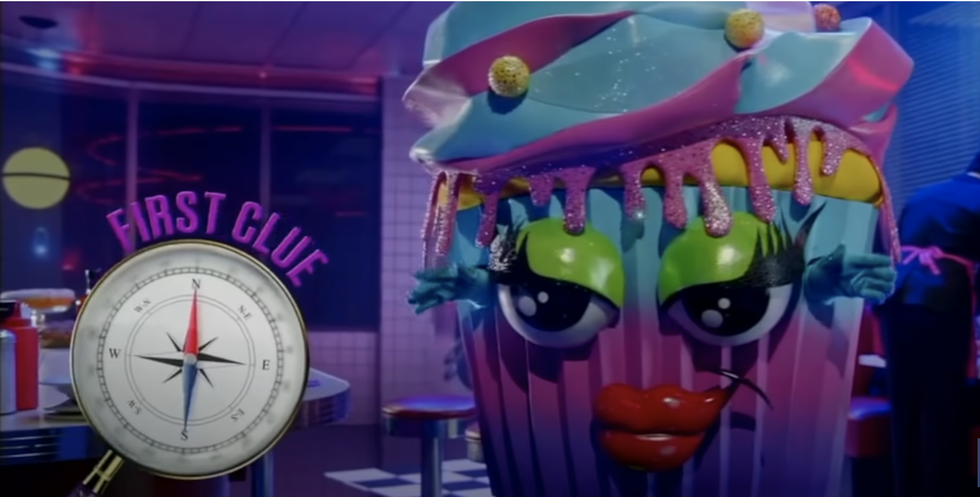 cupcake from the masked singer season 6 posing with a clue of a compass