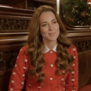 kate middleton sits in wooden pews wearing red sweater