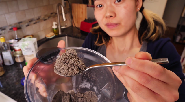 june holds a spoon of black sesame soup mix