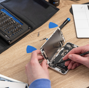 a set of hands dismantles and repairs an iphone